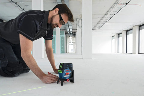 Pro Level 12V Green Beam Cross Line Laser With 100 Foot Reach And Smart Visimax Tech being used for alignment on a construction floor.