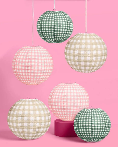 Six Pack Paper Camp Lantern Set In Pink Green And Tan For Bachelorette Parties Birthdays Outdoor Parties And Glamping Decor Includes Two Ten Inch Green Lanterns Two Twelve Inch Tan Lanterns And Two Twelve Inch Pink Lanterns Great For Party Vibes, displayed against pink background.