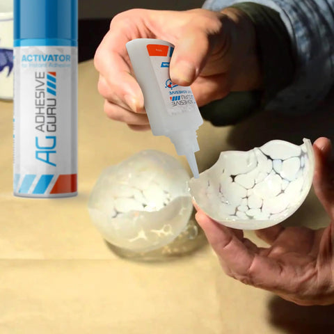 Adhesive Guru CA Glue with Activator bottle applying glue to cracked white ceramic sphere halves