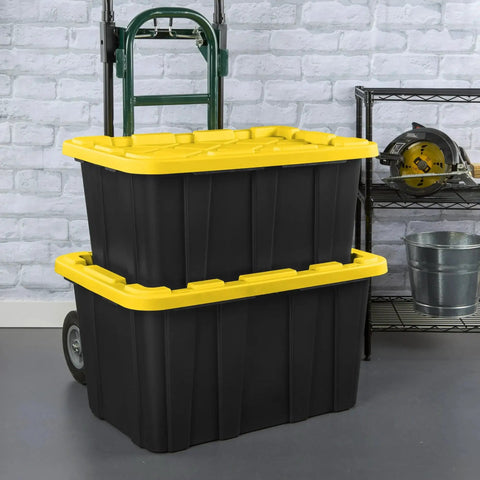 Two black and yellow Six Pack 27 Gallon Heavy Duty Industrial Totes with Locking Lids Stackable Plastic Storage Bins in workshop.