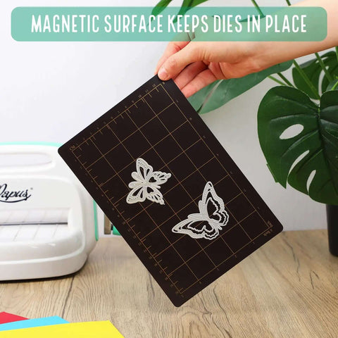 Hand holding Must Have Die Cutting Magnetic Shim Mat Set 6x9 Inch With Card Size Grids And Two Acrylic Cutting Plates For Die Cutting Machines Embossing And Crafting Accessories with metal dies on a grid.