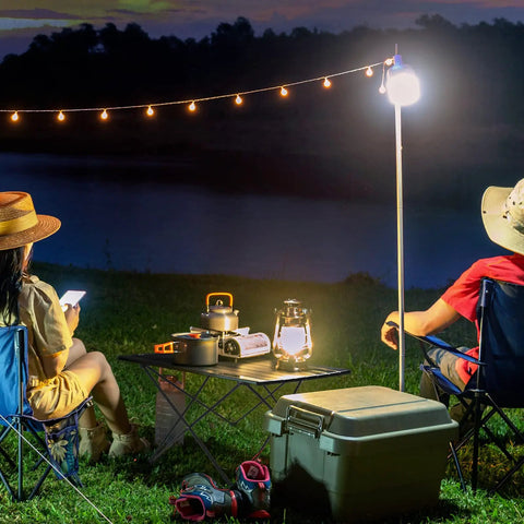 Ultralight Foldable Camping Side Table With Aluminum Build, set up at night by a lake, surrounded by camping gear and lights