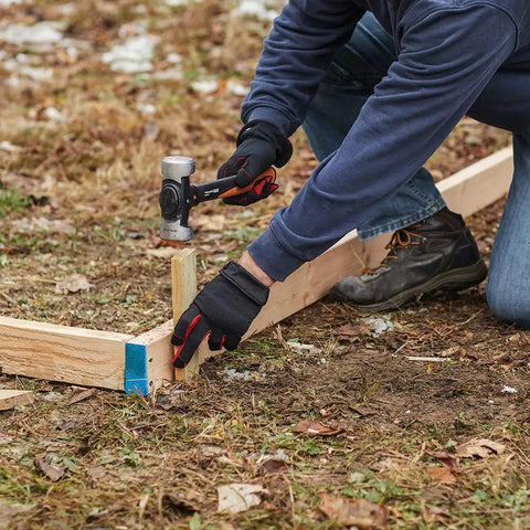 Person using IsoCore 4 lb Sledge Hammer for Demolition and Driving with Shock Reduction on a wooden stake outdoors.
