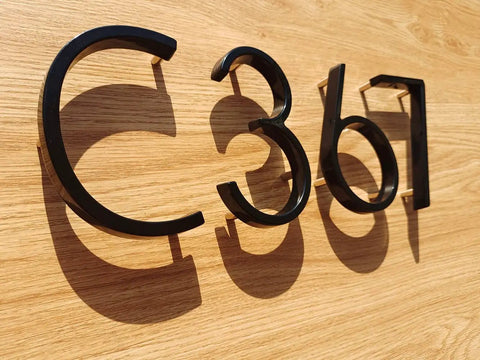 5 Inch Modern Floating Address Numbers For Houses In Rust Proof Zinc Alloy With A High Gloss Black Finish on wood surface
