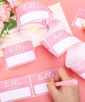 Light Pink Hello My Name Is Stickers Set, 300 Pcs Name Tag Labels On A Roll displayed on pink table with flowers