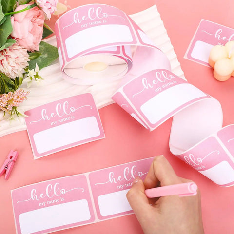 Light Pink Hello My Name Is Stickers Set, 300 Pcs Name Tag Labels On A Roll displayed on pink table with flowers