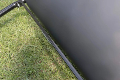Side view of 18 By 24 Inch Poly Lawn Roller For Push Or Tow Black Built Tough, showing metal frame on grass.
