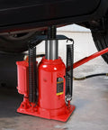 Close-up of Big Red 20 Ton Air Hydraulic Bottle Jack Heavy Duty Professional Lifting Tool in use under a vehicle.