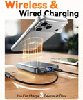 Heavy Duty Compact Magnetic Portable Charger And Serious 10000mAh Fast MagSafe Battery Pack charging a phone and earbuds on a wooden table.