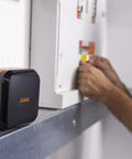 Portable Industrial Label Printer With Bluetooth And Pro Label Tool App Hands Free Belt Clip For Tight Jobsite Spaces Rechargeable Battery Prints Durable Labels Up To 1 Inch Industrial Formats on a metal surface in a worksite.