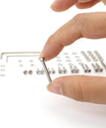 Close-up of a hand holding a screw from 50 Piece Turntable Headshell Mounting Hardware Kit Stainless Steel Hex Socket Head Screws Bolts Nuts Washers And Wrenches In A Mixed Box Case Color Silver For Phonograph Parts Ready To Install.