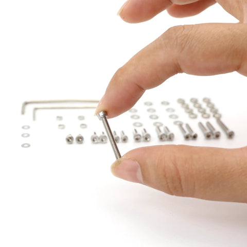 Close-up of a hand holding a screw from 50 Piece Turntable Headshell Mounting Hardware Kit Stainless Steel Hex Socket Head Screws Bolts Nuts Washers And Wrenches In A Mixed Box Case Color Silver For Phonograph Parts Ready To Install.