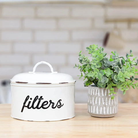 Basket Style White Enamel Coffee Filter Holder, The Go To Rustic Farmhouse Distressed Look, next to a potted plant on a kitchen counter