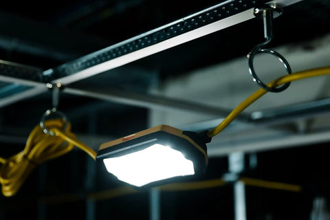Heavy Duty 100 FT LED String Work Lights X Shaped Uplight hanging from a hook, providing bright illumination in a dark space.