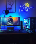 King Neon Sign Blue Letters LED Neon Light With Pink Crown Wall Decor For Bedroom Kids Room Teen Boys Room Birthday Wedding Party Bar Decor USB Powered Plug In Easy And Vibe Ready To Shine illuminating a gaming setup with blue and pink glow