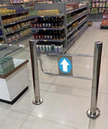 Solid Self Closing Safety Gate With Hassle Free Post Mount, Ninety Degree Spring Loaded Swing Door For Store Aisles, One Way Access Barrier, No Sweat Automatic Closing, Silver Plated in a retail setting.