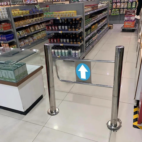 Solid Self Closing Safety Gate With Hassle Free Post Mount, Ninety Degree Spring Loaded Swing Door For Store Aisles, One Way Access Barrier, No Sweat Automatic Closing, Silver Plated in a retail setting.
