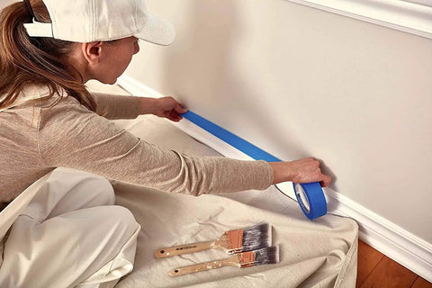 Person using blue tape on wall with brushes on Heavy Duty Cotton Canvas Drop Cloths 4x5 Feet Pack Of 4 Thick Painter Cloths