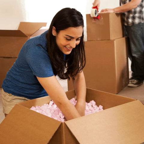 Person packing Solid Antistatic Packing Peanuts In Bulk Six Cubic Feet Of Super Snug White Cushioning in a cardboard box.