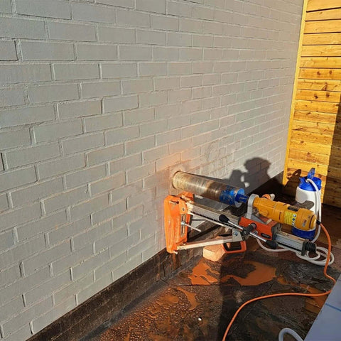 SALI wet diamond core drill system mounted on brick wall for masonry drilling; orange base, blue head, yellow motor.
