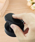 Hand holding 2 Pack Powerful Suction Cup Handles for glass mirrors doors cabinets and bathrooms, black ABS construction on wood surface.