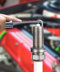Close-up of steel feeler gauge set with dual metric/imperial blades measuring a gap on a threaded metal fitting