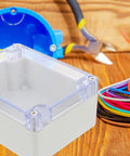 Sturdy White Plastic Junction Box With Clear Dustproof Cover For Electrical Project Setups on wood surface with wires and tools.