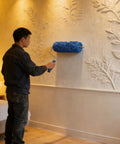 Premium 5 Inch Rubber Patterned Paint Roller Featuring An Ergonomic Handle used by a person painting a decorative wall.