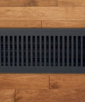 4 X 10 Cast Aluminum Contemporary Vent Cover in black installed on wooden floor