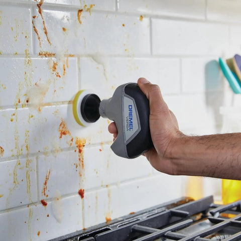 Tackle Stubborn Dirt Effortlessly With This Rechargeable Electric Scrubber Cleaning Kit Featuring Ten Plush Sponge Pads For No Sweat Tile Scouring That Delivers Butter Smooth Shine Across Every Hard Surface At Home. Person using electric scrubber on dirty white tile backsplash.