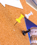 Three Killer 600 Color Push Pins With Solid Steel Points for Bulletin Boards used on a cork board in vibrant yellow, white, and black.