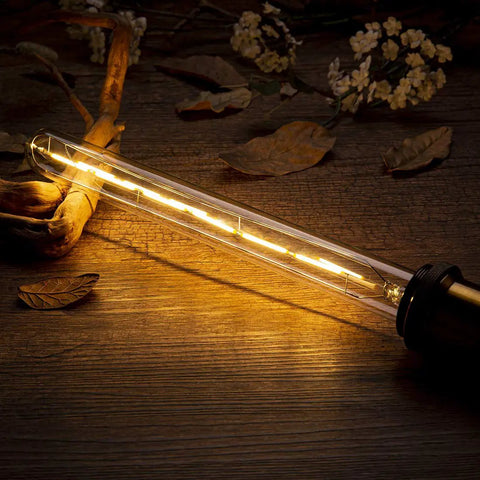 Dimmable T10 LED Filament Tubular Bulb 6W Warm White 2700K 11.8 Inch Long Tube glowing on a rustic wooden surface