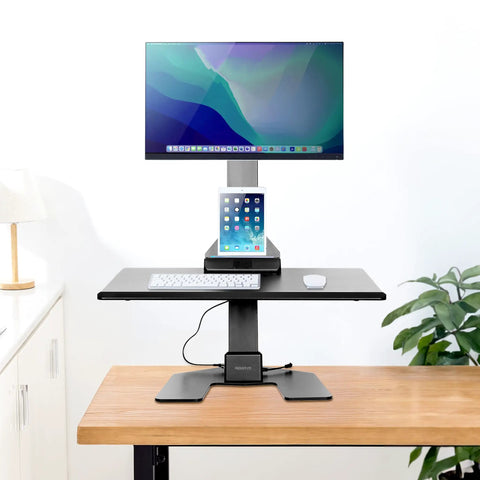 Heavy Duty Electric Standing Desk Converter With Monitor Mount And Wide Keyboard Tray on a wooden table with a displayed monitor.