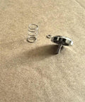 Premium Metal Shutter Replacement Button For Compact Cameras Featuring Smooth Snap Action And A Dead Simple Drop In Install Process For Quick Home Repairs Today Snazzy Look And Reliable Performance with spring and retaining clip on a flat surface.
