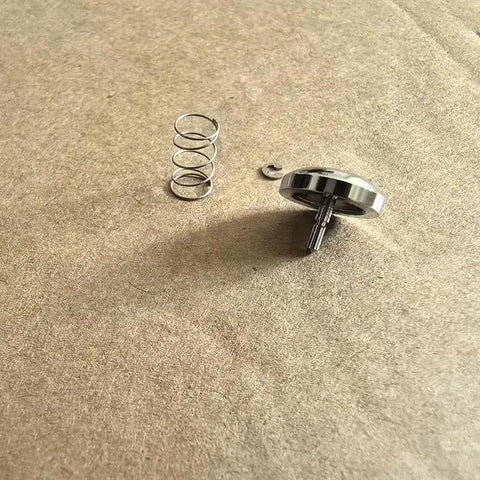 Premium Metal Shutter Replacement Button For Compact Cameras Featuring Smooth Snap Action And A Dead Simple Drop In Install Process For Quick Home Repairs Today Snazzy Look And Reliable Performance with spring and retaining clip on a flat surface.