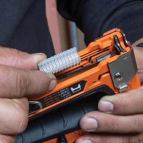 Close-up of Heavy Duty Cable Stapler Built Tough For Voice Data Video And Nonmetallic NM Cable in use with insulated staples and lever.
