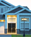Front view of a house with an Outdoor Lamp Post Light with Three Heads in Old School Black and Clear Glass Panels, E26 Base, 100W Max, lit at dusk.