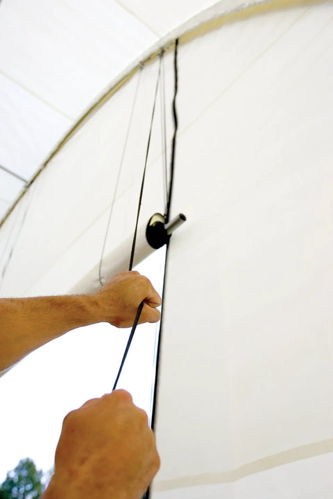 Hands using Pull-Eaze Roll Up Door Kit for Shelters With Easy One Pull Access, showing marine grade nylon rope and pulley system.