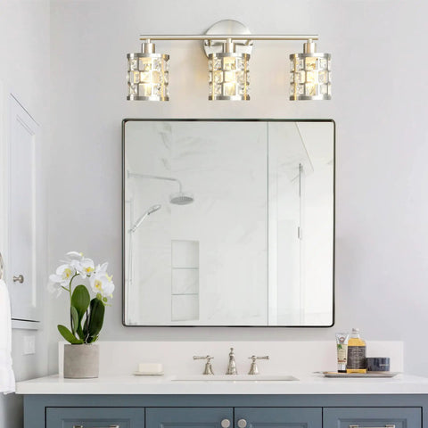 Three Light Brushed Nickel Vanity Light Fixture With Cylinder Crystal Shades Over Mirror Slick Modern Wall Sconce in bathroom