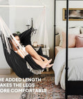 Woman relaxing in hammock chair with foot rest and cushions for ultra cozy comfort supports up to 500 pounds indoors
