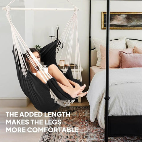 Woman relaxing in hammock chair with foot rest and cushions for ultra cozy comfort supports up to 500 pounds indoors