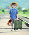 Young boy with toy and 14 Inch Underseat Carry On Luggage With Wheels, Dark Green on train tracks.