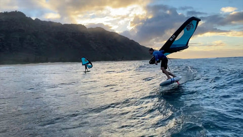 Two people surfing with Alien Wing 6M High Performance Wind Wing For Foiling And Surfing Lightweight Aerodynamic Rigid Wing Includes Backpack Wrist Leash And Repair Kit Tri Color near coast.