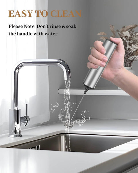 Person holding Rechargeable Milk Frother With USB, Portable Handheld Whisk, Silver, next to running kitchen faucet.