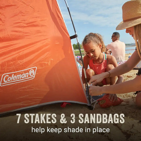 Lightweight Beach Shade Tent with pre attached poles, side view, sand setup, showing 7 stakes, 3 sandbags, family nearby