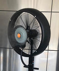 No Sweat Commercial Misting Fan Delivers Beast Mode High Velocity Airflow For Restaurants And Warehouses Featuring Rock Solid Metal Housing And Quick Adjustable Tilt Swivel In Blue, close-up view of fan with mist.
