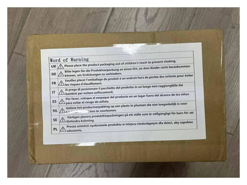 Box with multilingual safety warning label displayed on top, placed on wooden floor.