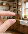 Close-up of a hand holding a miniature teacup from the 3-Piece Antique Bronze Teacup Hinge Heads Decorative Topper Set for Doors.