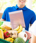 Person holding groceries with a 10 Pack Padded Bubble Mailer Bags 25 By 30 Cm Plus 4 Cm Self Sealing Cushioned Envelopes visible