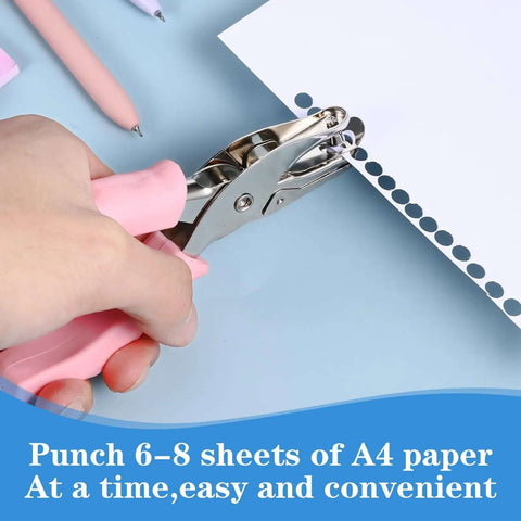 Using a pink handheld one quarter inch hole punch for crafts on paper, shows grip handles, part of 12 pcs multicolor set.